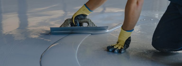 The worker applies gray epoxy resin to the new floor