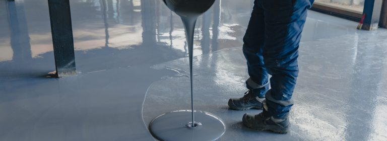 The worker applies gray epoxy resin to the new floor