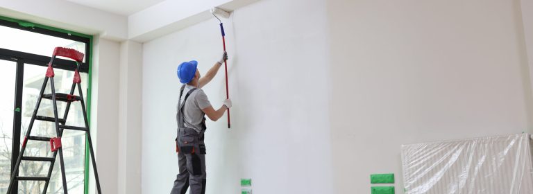 Male painter paints house wall with roller brush. Decoration and improvement interior concept.